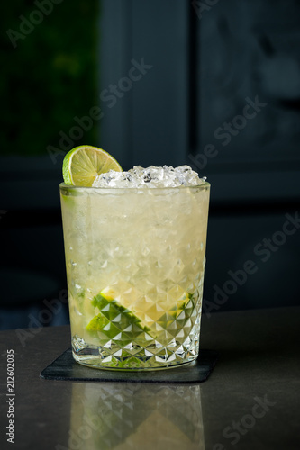 cold cocktail with lime and lemon. A glass of dew drops. Freshness, alcohol, bar. Black background