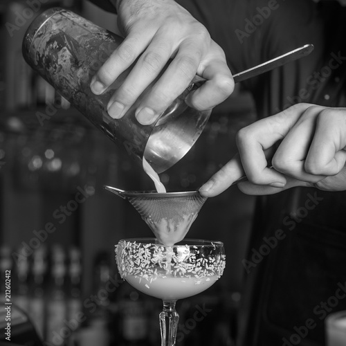 The bartender makes a cocktail of coconut and ice. Macro, black background, hand, white photo