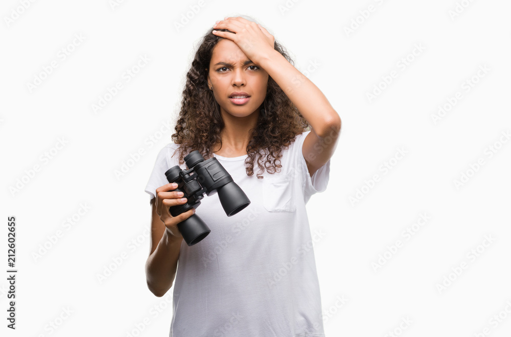 Young hispanic woman looking through binoculars stressed with hand on head, shocked with shame and surprise face, angry and frustrated. Fear and upset for mistake. Young hispanic woman looking through binoculars stressed with hand on head, shocked with shame and surprise face, angry and frustrated. Fear and upset for mistake.