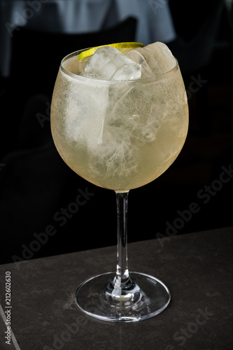 a bartender makes a summer cocktail of lime and ice. Macro, black background, hand, yellow, drops on glass, bubbles photo