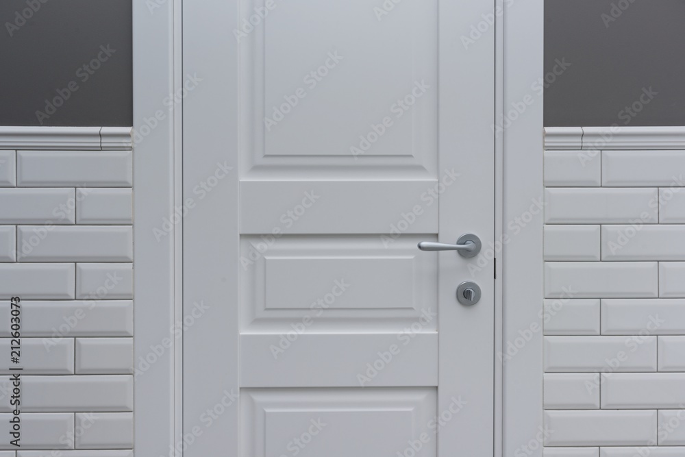 White door in the bathroom toilet room. Background gray painted wall