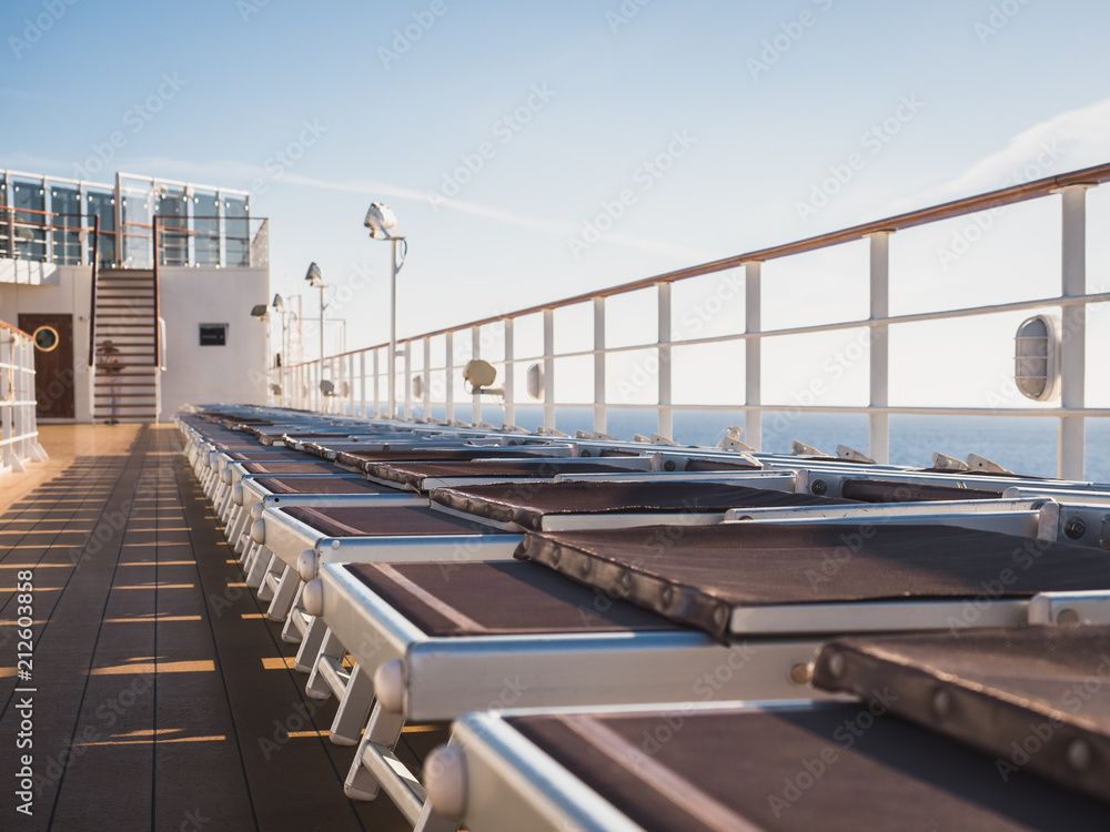 Naklejka premium Empty sea deck of a cruise ship at dawn in the open sea against a blue sky and a bright sun