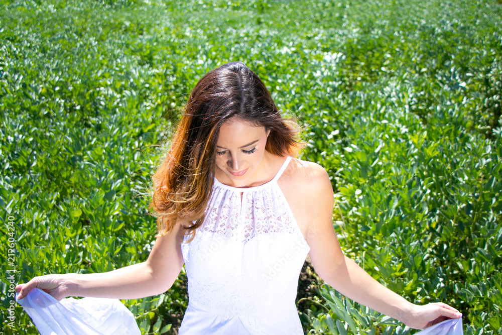 Beautiful woman, bride with blue eyes and brown hair walks through crop field on a sunny summer's day Beautiful woman, bride with blue eyes and brown hair walks through crop field on a sunny summer's day