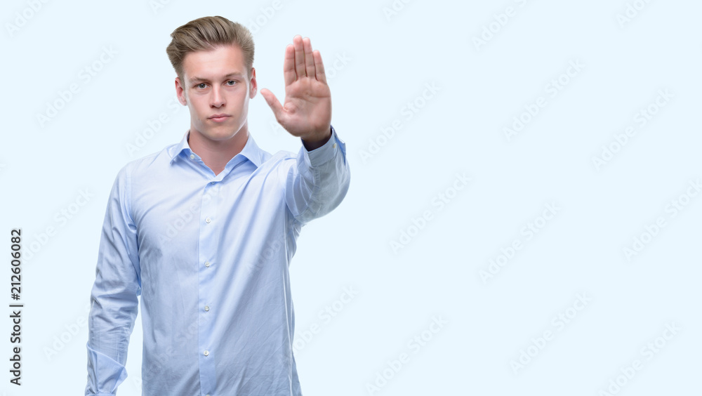 Young handsome blond man with open hand doing stop sign with serious and confident expression, defense gesture Young handsome blond man with open hand doing stop sign with serious and confident expression, defense gesture