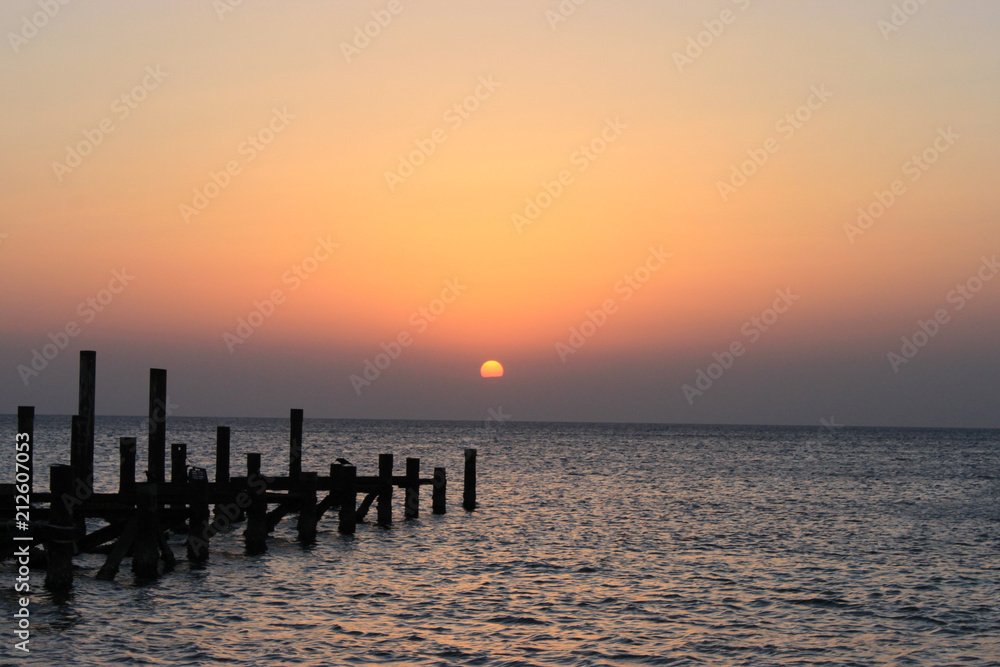 Sunrise on the sea. The sun peeps out from behind the clouds.  Red sea, Safaga, Egypt.