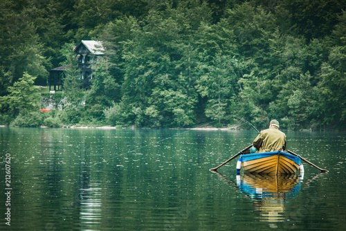 retired old man fishing from boat at lake