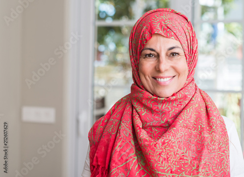 Middle aged muslim woman wearing hijab with a happy face standing and smiling with a confident smile showing teeth