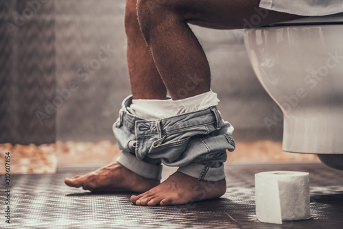 Close up Young Afro-American Man Sitting on Toilet