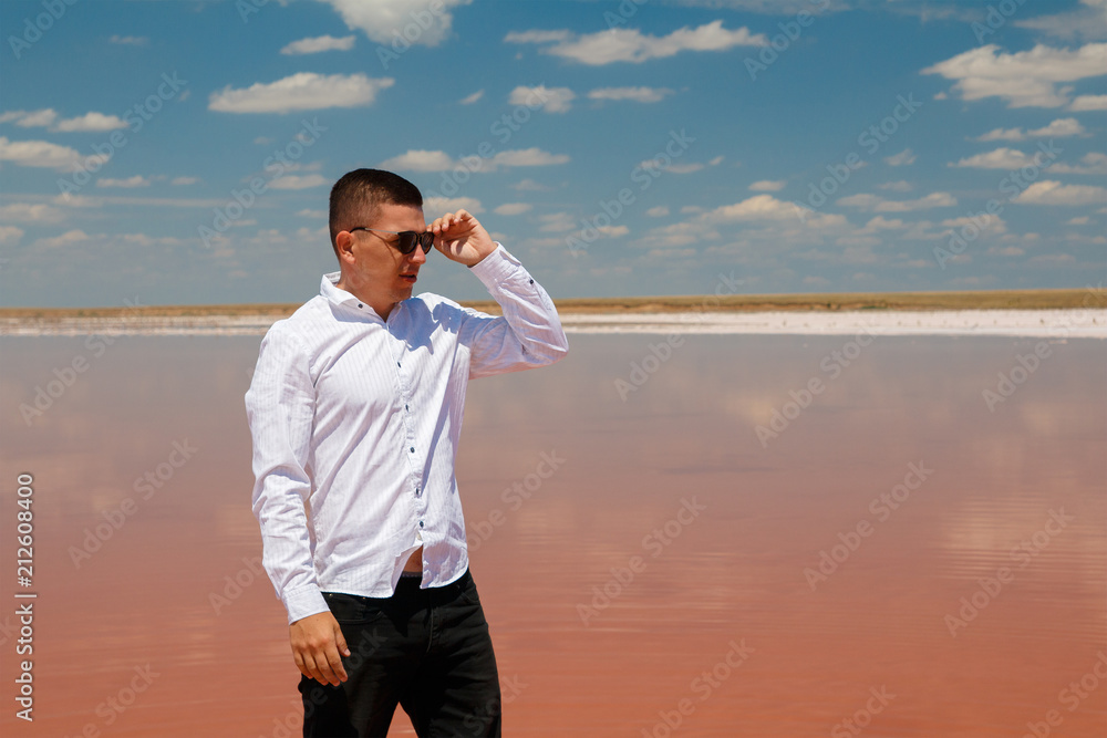 Young man in white shirt is standing in a pink lake
