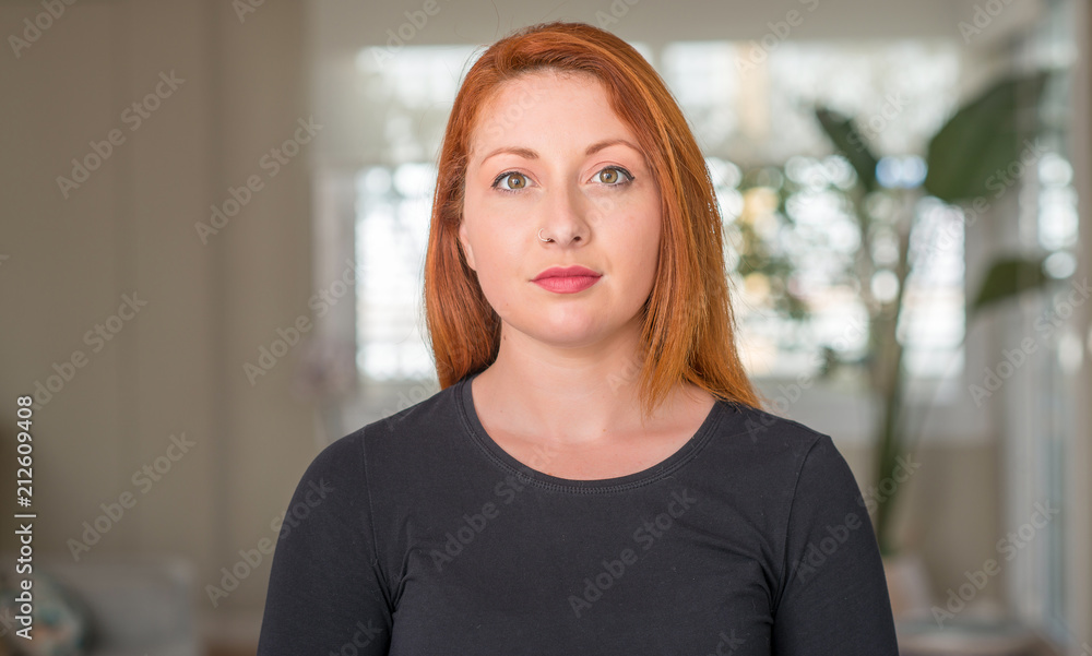 Redhead woman at home with a confident expression on smart face thinking serious