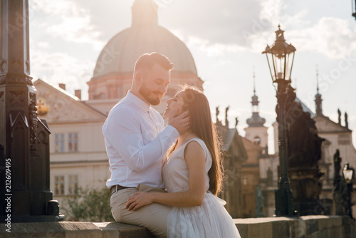 Romantic wedding couple of groom and bride hugging and kissing on the Charles bridge in the old city with beautiful architecture. Prague, Czech Republic. Sunset