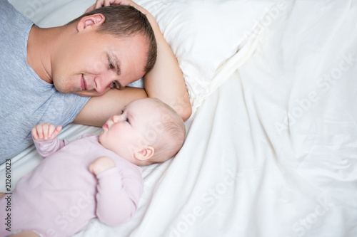 close up of young father lying with baby girl on the bed with copy space