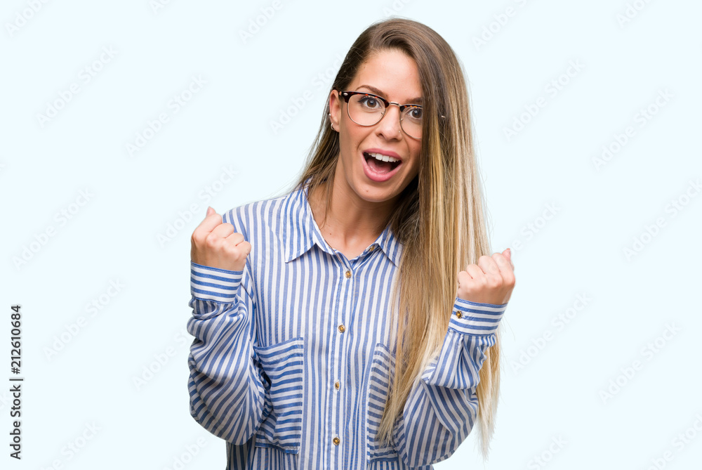 Beautiful young woman wearing elegant shirt and glasses celebrating surprised and amazed for success with arms raised and open eyes. Winner concept.