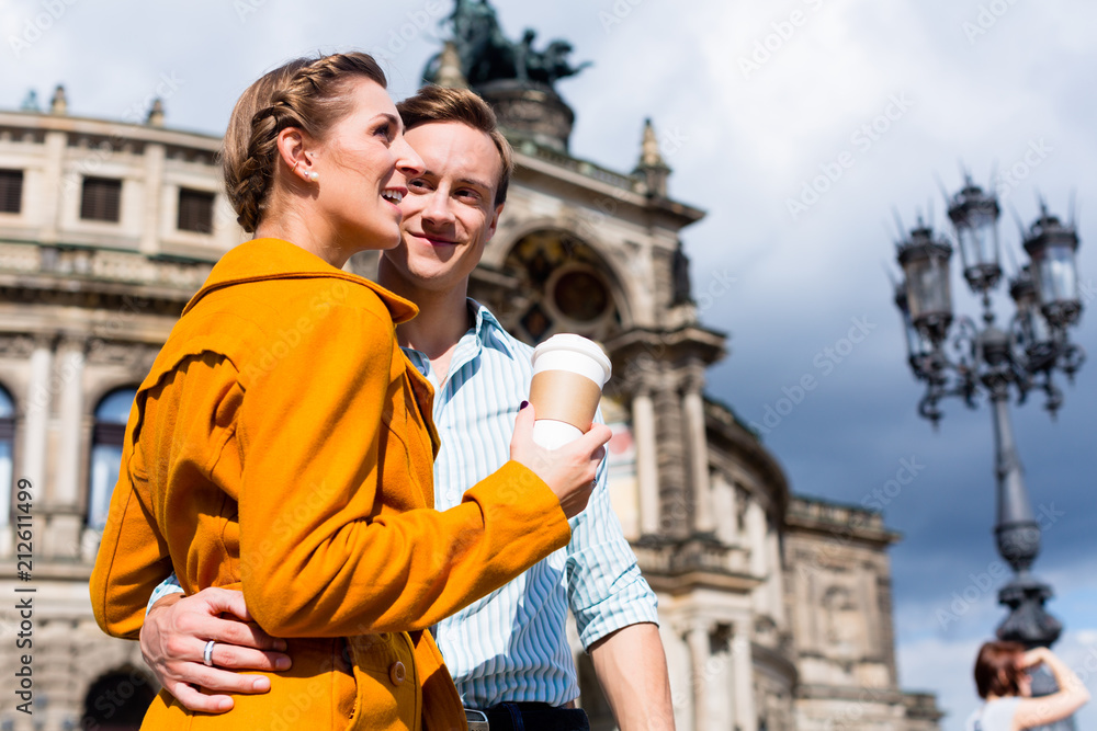 Tourist couple at Semperoper in Dresden having walk with coffee to takeaway
