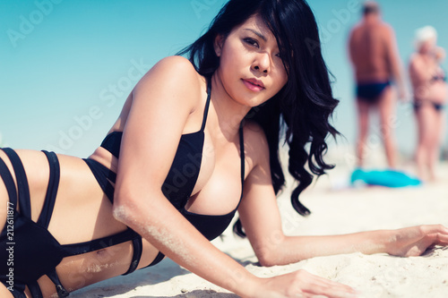 Sexy Asian woman on beach vacation lying in water wearing swimwear