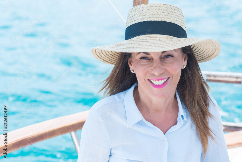 Beautiful middle age woman traveling on sailboat and smiling happy and confident.