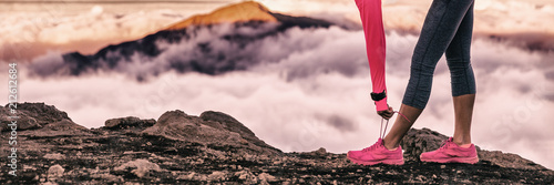 Fototapeta Kobieta biegacz przygotowuje się do szlaku uruchomić w wysokości wulkanu tle góry wiązanie sznurówek do biegania. Motywacja fitness i sport zdrowego stylu życia. Panorama banera.