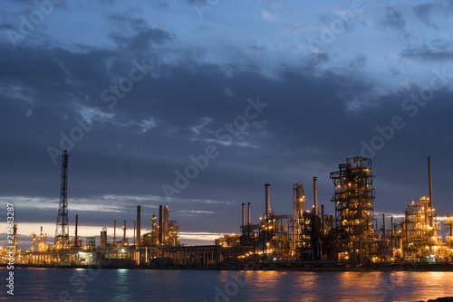 Petroleum refinery factory on water coast at dusk