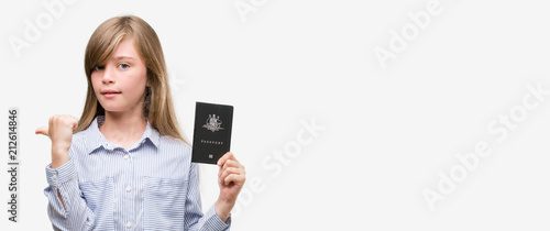 Young blonde toddler holding australian passport pointing with hand and finger up with happy face smiling