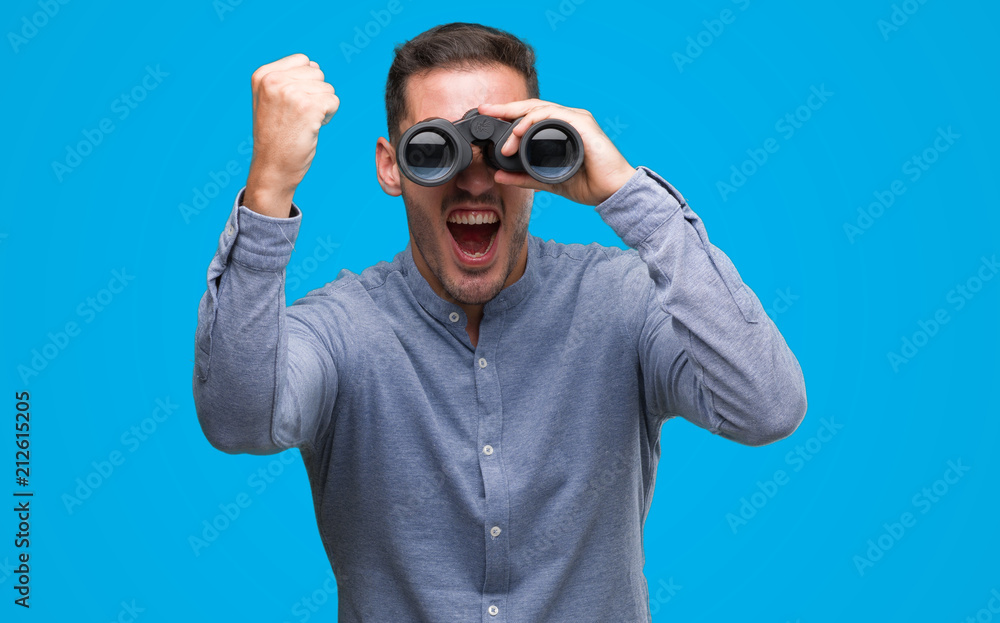 Handsome young man looking through binoculars annoyed and frustrated shouting with anger, crazy and yelling with raised hand, anger concept Handsome young man looking through binoculars annoyed and frustrated shouting with anger, crazy and yelling with raised hand, anger concept