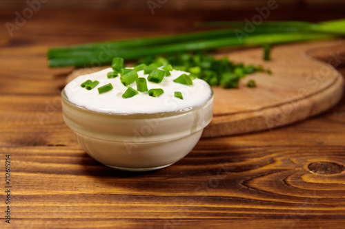 Sour cream and green onion on wooden table