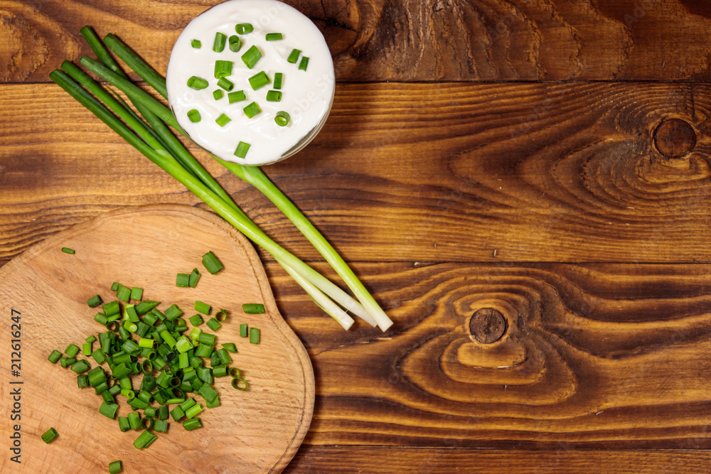 Sour cream and green onion on wooden table. Top view Sour cream and green onion on wooden table. Top view