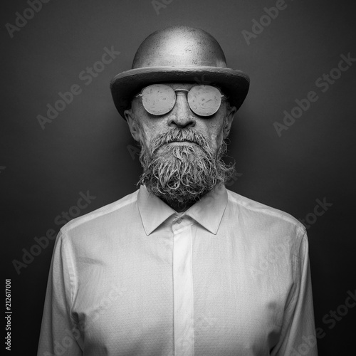 Portrait of a bearded man in with sunglasses. The face is covered with clay