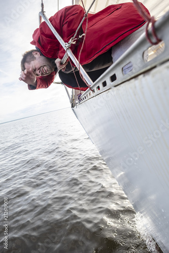 Foto A man in a red jacket suffers from seasickness while walking on a yacht