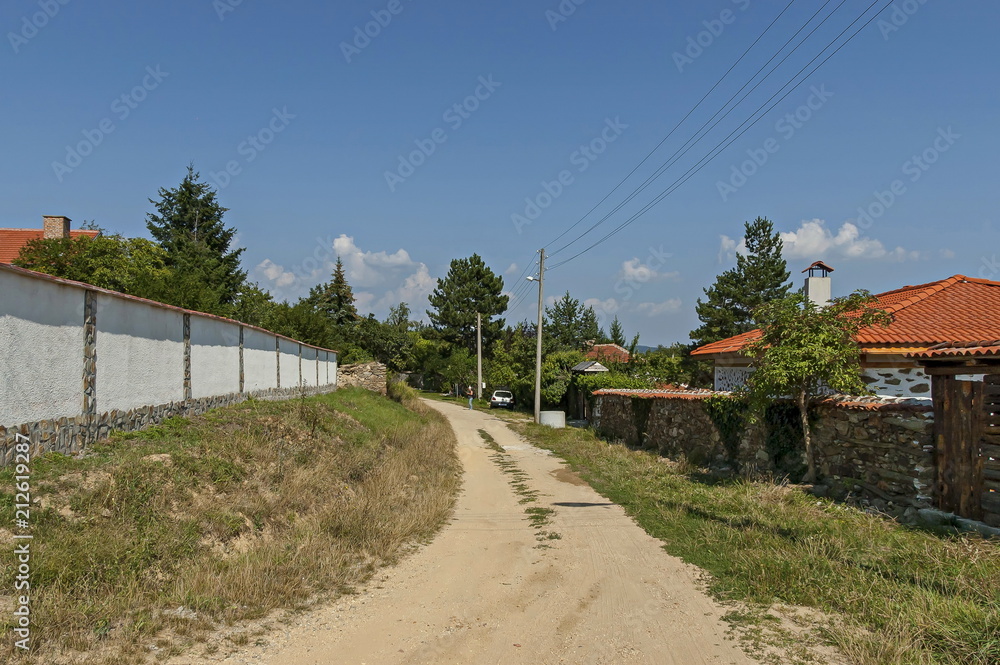 Part of street in the Paunovo village with old house, tree and fence, Sredna Gora mountain, Ihtiman, Bulgaria, Europe  