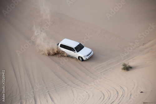 Luxurous white SUW 4x4 drifts on desert safari on dunes exreme racing in arabia travel rally on sand in sports vehicle
