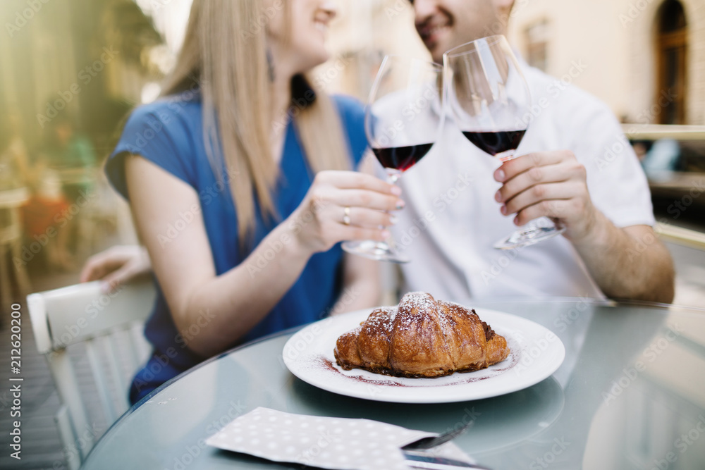 Cheerful couple in a restaurant with glasses of red wine.  Young couple with glasses of red wine in a restaurant with city view