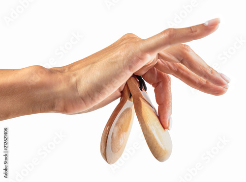 castanets in the hand of a young girl with thin graceful fingers on a white background photo