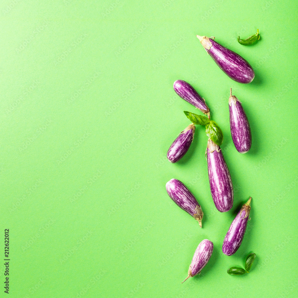 Heap of small eggplant or aubergine vegetable with basil leaves on green background. Healthy food concept with copy space. Heap of small eggplant or aubergine vegetable with basil leaves on green background. Healthy food concept with copy space.