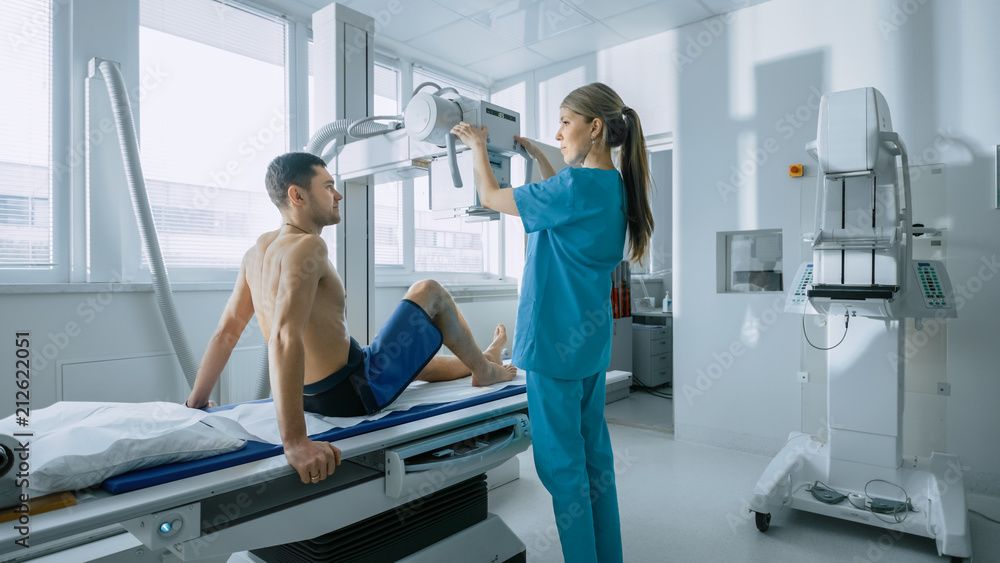 Obraz premium In the Hospital, Man Sitting on a Bed, Female Technician adjusts X-Ray Machine for Scanning His Leg for Injury. Scanning for Fractures, Broken Limbs, Injuries, Cancer or Tumor. Modern Hospital.