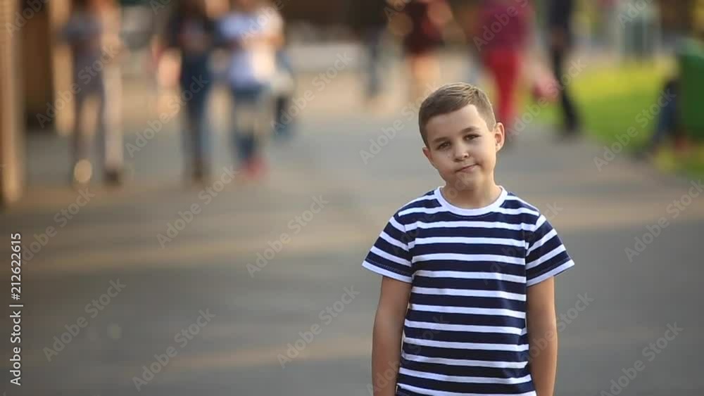 A little boy in a striped T-shirt is smiling and cheering.Spring, sunny weather A little boy in a striped T-shirt is smiling and cheering.Spring, sunny weather