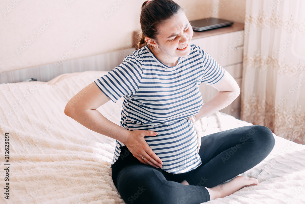 Obraz premium pregnant woman has pain in belly, she touch her belly