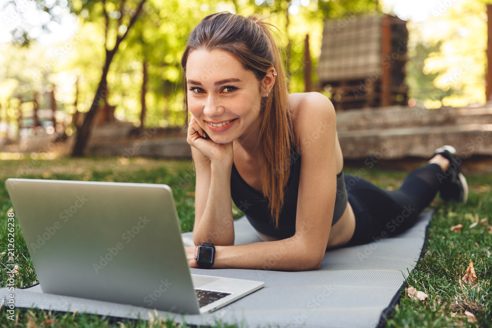 Portrait of a smiling young fitness girl using laptop Portrait of a smiling young fitness girl using laptop