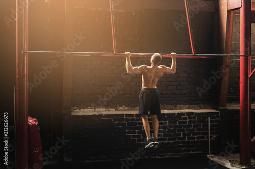 Strong man doing pull up exercise in the gym photo