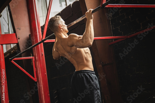 Obraz na plátně Strong man doing pull up exercise in the gym