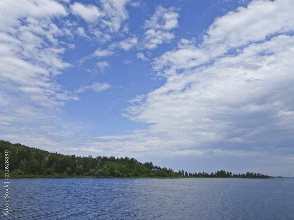 Summer landscape: blue sky and cirrus clouds over the lake on a sunny day