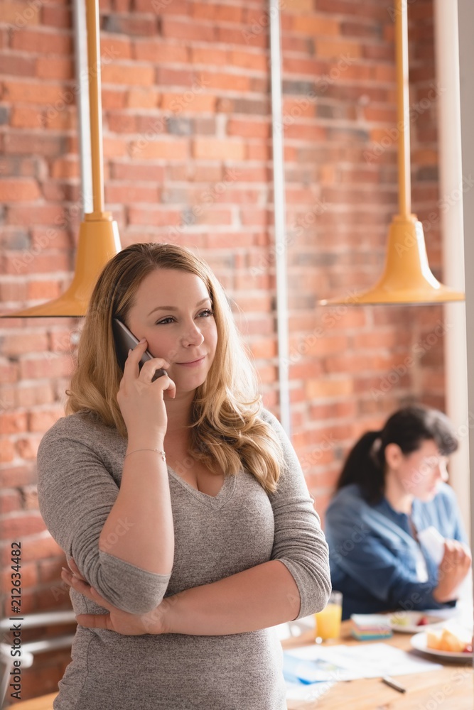 © Wavebreak Media - Businesswoman talking on smartphone while standing in office © Wavebreak Media - Businesswoman talking on smartphone while standing in office