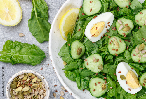 Useful spinach salad, cucumbers, eggs and seeds (pumpkin, flax and sunflower) with lemon and olive oil. Dietary food. Healthy Breakfast or dinner. Selective focus