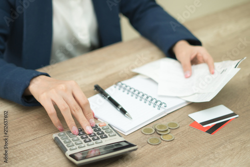Business woman using calculator and thinking about cost on desk at home office.