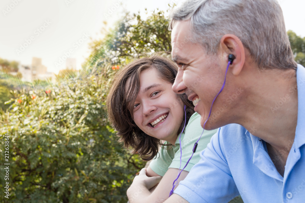 Mature dad and teenager son. Father Day. Man is listening to music with son. Concept of family, different generations, bonding, connection. Mature dad and teenager son. Father Day. Man is listening to music with son. Concept of family, different generations, bonding, connection.