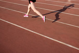 Athletic young woman in pink sneakers run on running track stadium