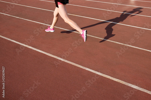 Athletic young woman in pink sneakers run on running track stadium © Kiryl Lis