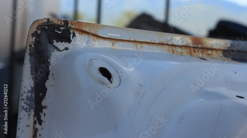 A high pressure sand blaster blows away rust and corrosion from an old car part.