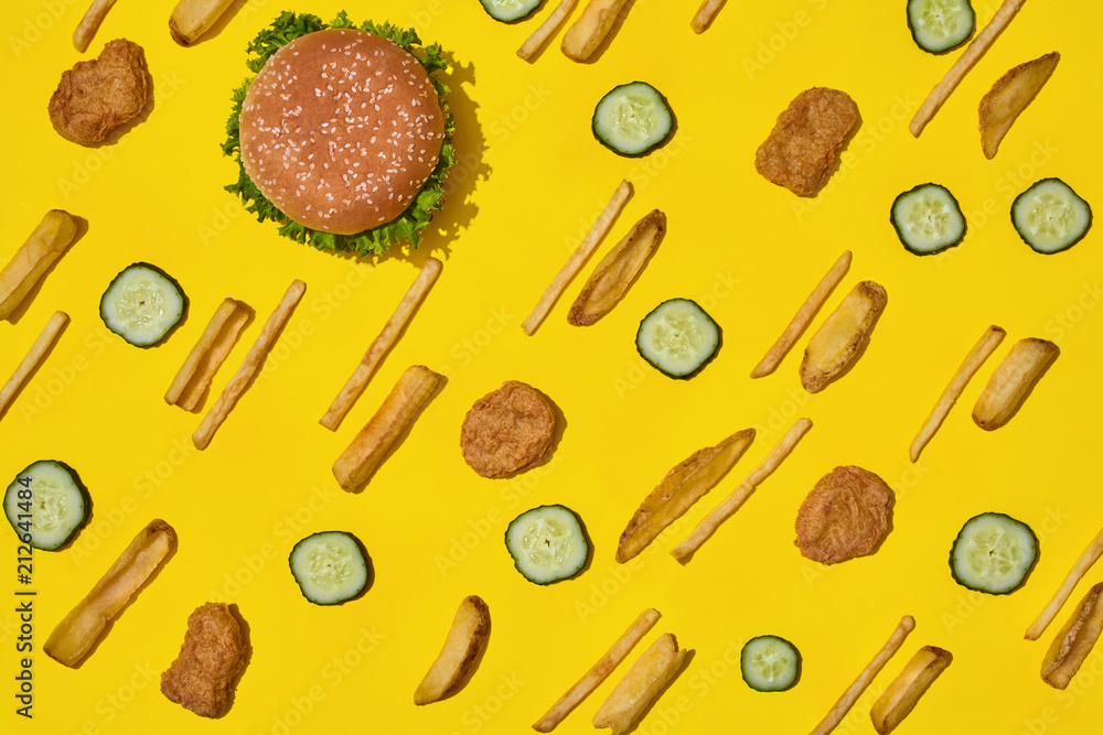 Most popular fast food meal. Chicken nuggets, burger and french fries on yellow background top view Most popular fast food meal. Chicken nuggets, burger and french fries on yellow background top view