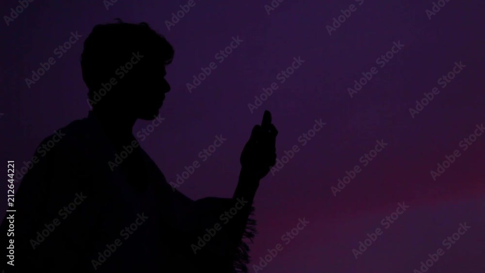 Silhouette of a young man with no network coverage in outside during sunset Silhouette of a young man with no network coverage in outside during sunset