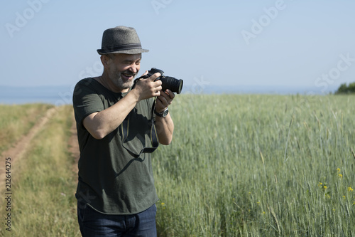 A man with a camera on the background of a wheat field. Concept: summer vacation.